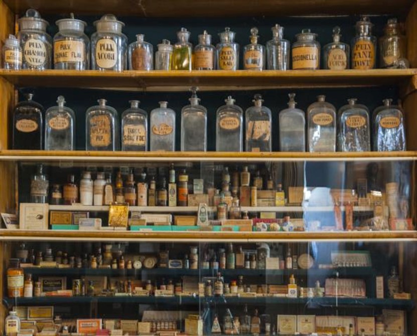 Regal einer alten Apotheke, woll mit alten Flaschen. Bild ist Teil des Blogtextes bei Acala über koloidales Silber