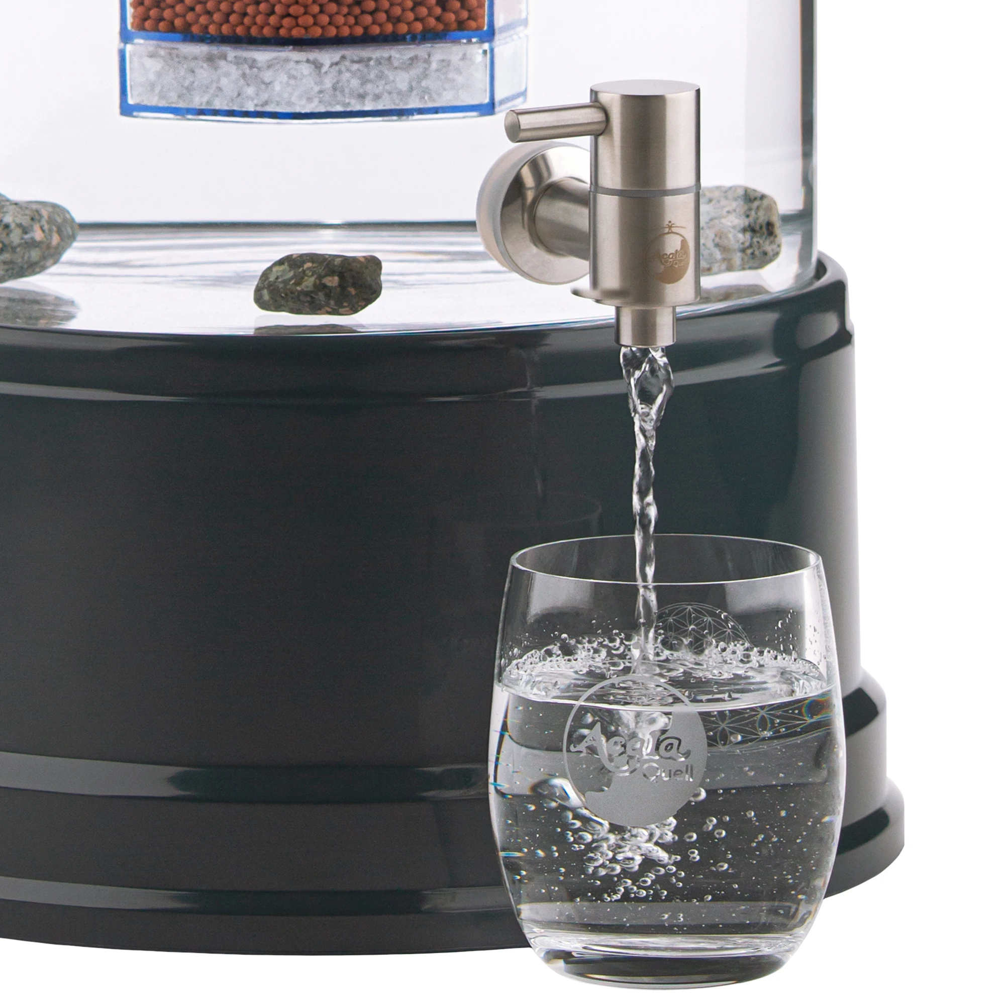 Zu sehen ist der Edelstahl Wasserhahn Makino für Standfilter an einem Glastank in kristallklar montiert. Der Hahn ist silber, man sieht das AcalaQuell Logo darauf. Der Hebel zum öffnen ist nach links gedreht, Wasser läuft in ein darunter stehendes Glas.