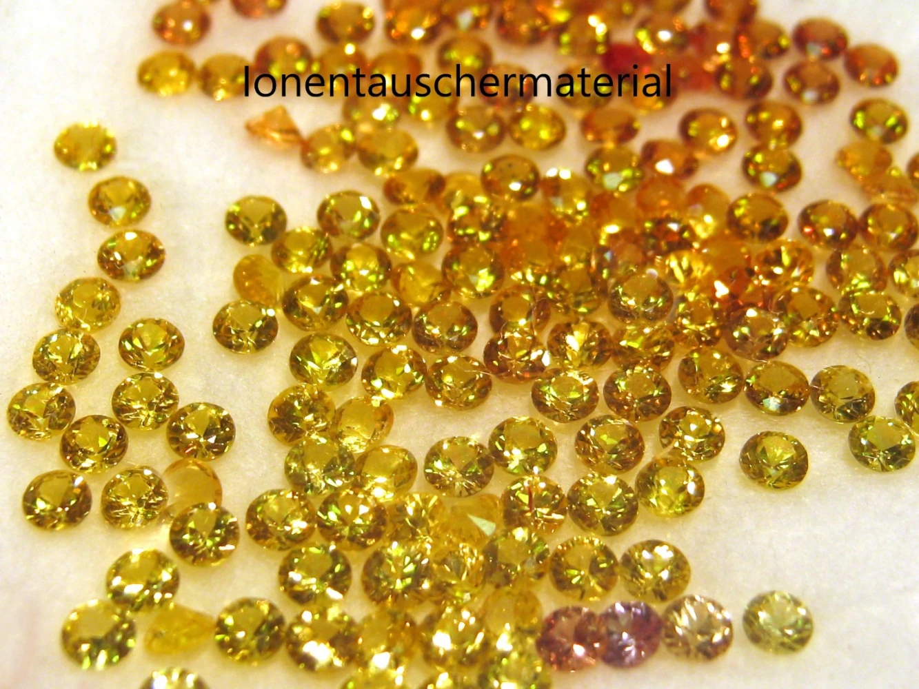 Auf dem Bild sind goldene Harzkügelchen zu sehen, die mit Ionen geladen sind und als Ionentasuchermaterial verwendet werden