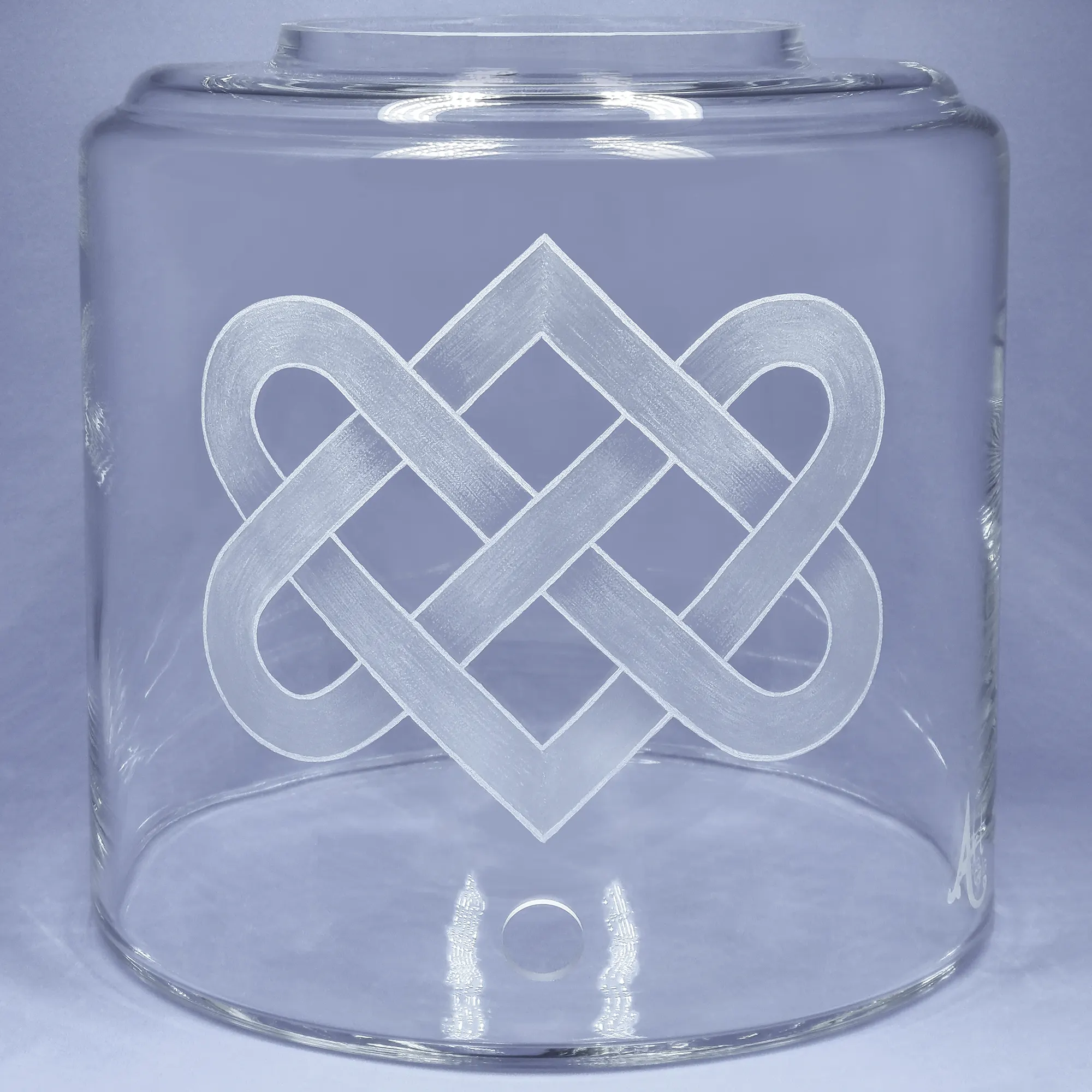 Vorratstank für einen Acala Wasserfilter aus klarem Glas auf, dass der Liebesknoten graviert ist.