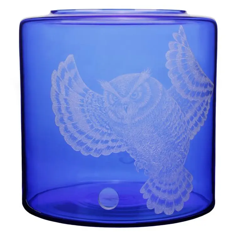 Vorratstank für einen Acala Wasserfilter Mini mit einer Handgravur. Die Gravur zeigt, auf blauem Glas, eine Eule mit ausgebreiteten Flügeln. Sehr filigran graviert.Ansicht von vorne.