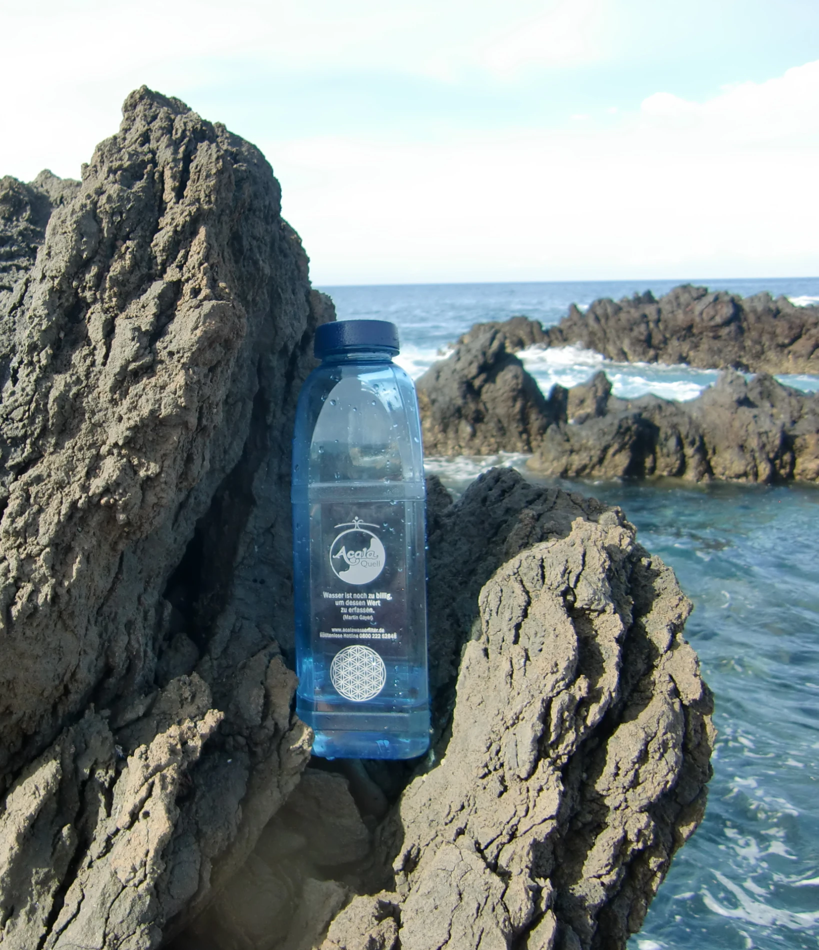 eine Tritanflasche in blau steht auf einem Felsen