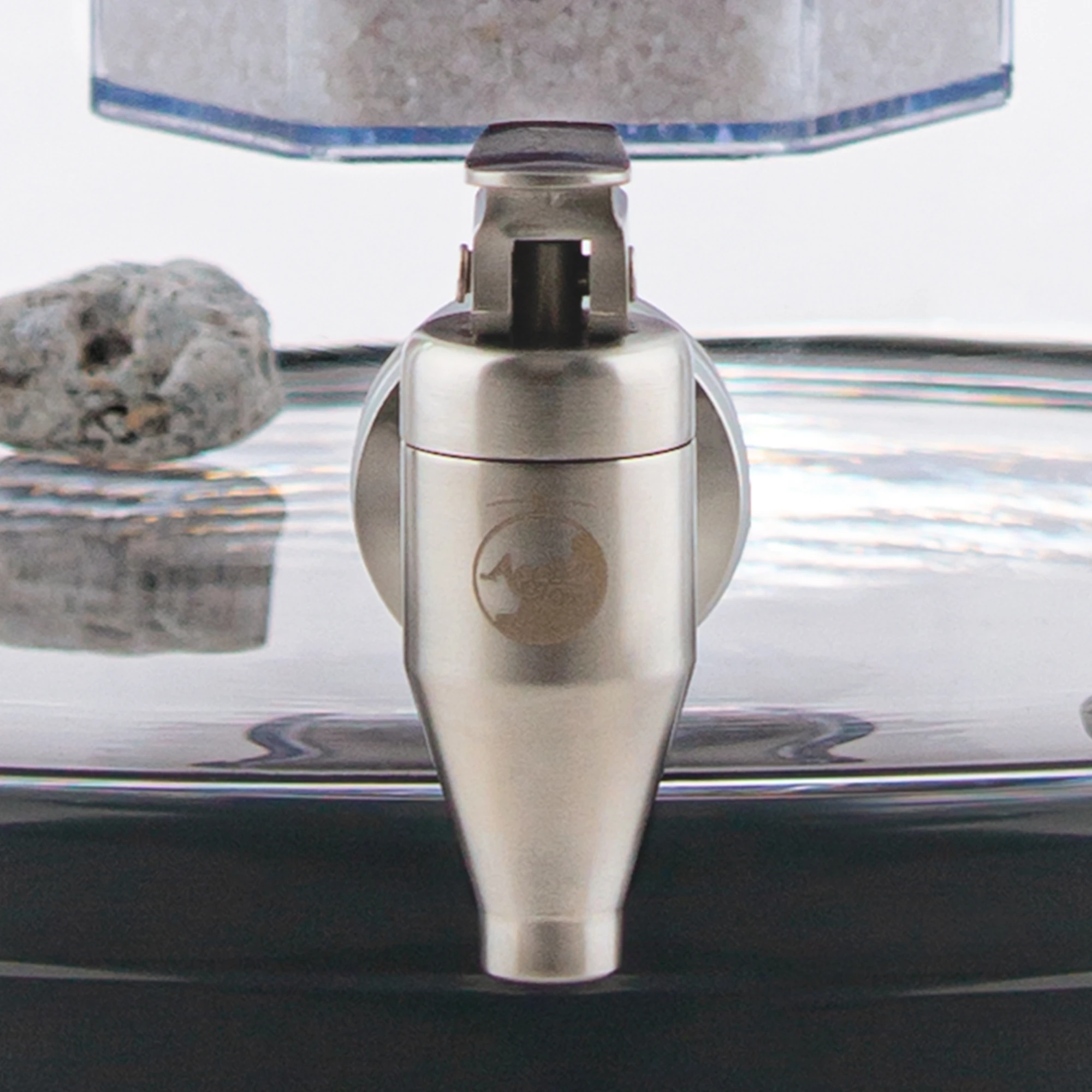 Zu sehen ist der Edelstahl Wasserhahn Yamashita für Standfilter an einem Glastank in kristallklar montiert. Der Hahn ist silber, man sieht vorne das AcalaQuell Logo darauf. Der Hebel zum öffnen ist nach vorne gedreht.