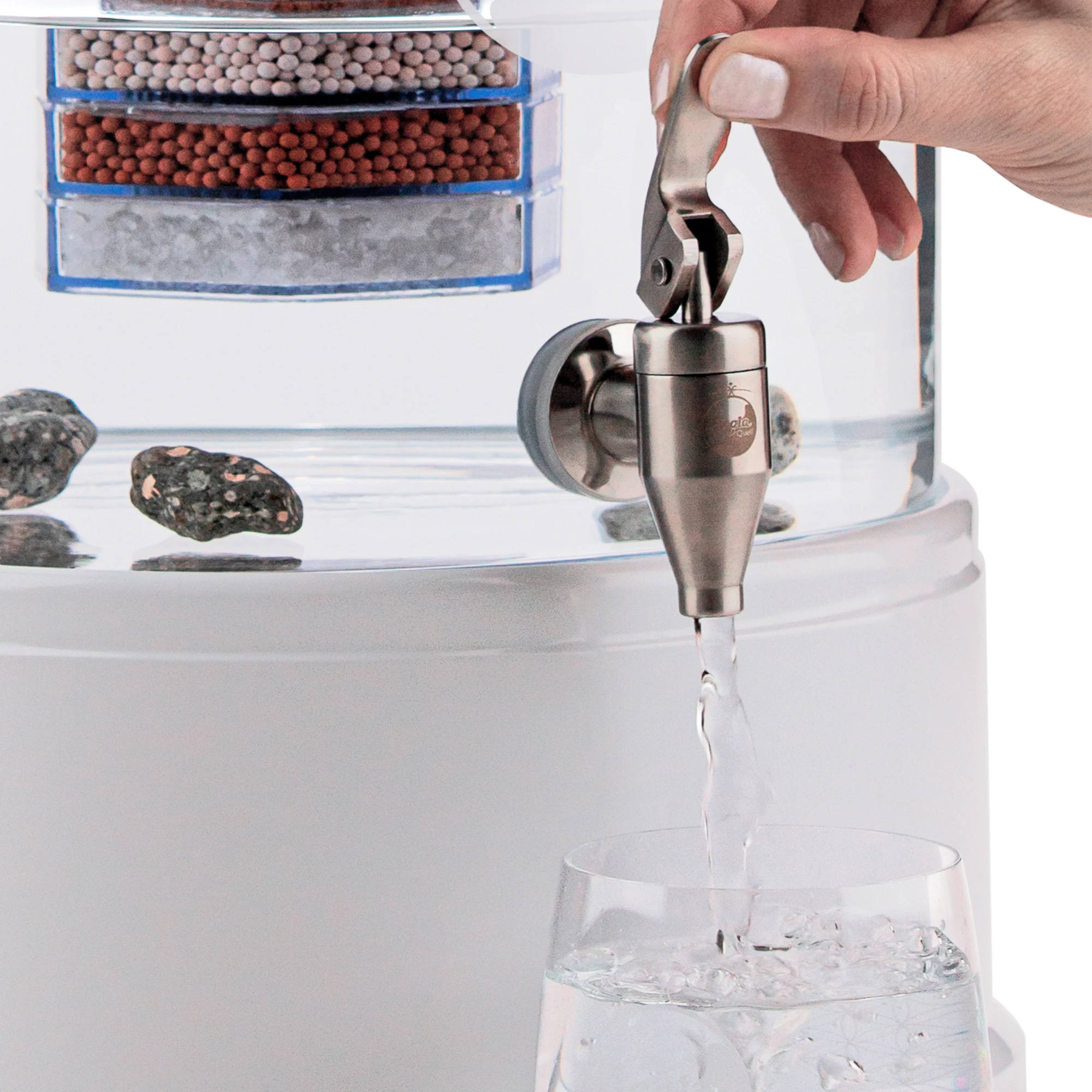 Zu sehen ist der Edelstahl Wasserhahn Yamashita für Standfilter an einem Glastank in kristallklar montiert. Der Hahn ist silber, eine Hand drückt den Hebel zum öffnen nach oben, Wasser läuft in ein darunter stehendes Glas.